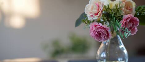 Un vase en verre transparent contenant des fleurs roses et blanches, posé sur une surface réfléchissante.