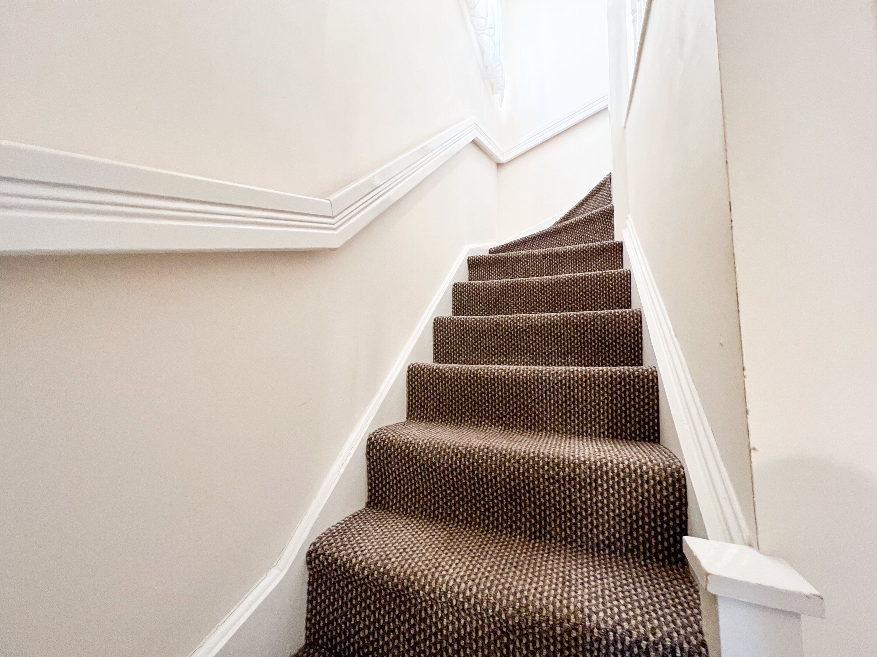 A staircase with a patterned carpet and white walls.