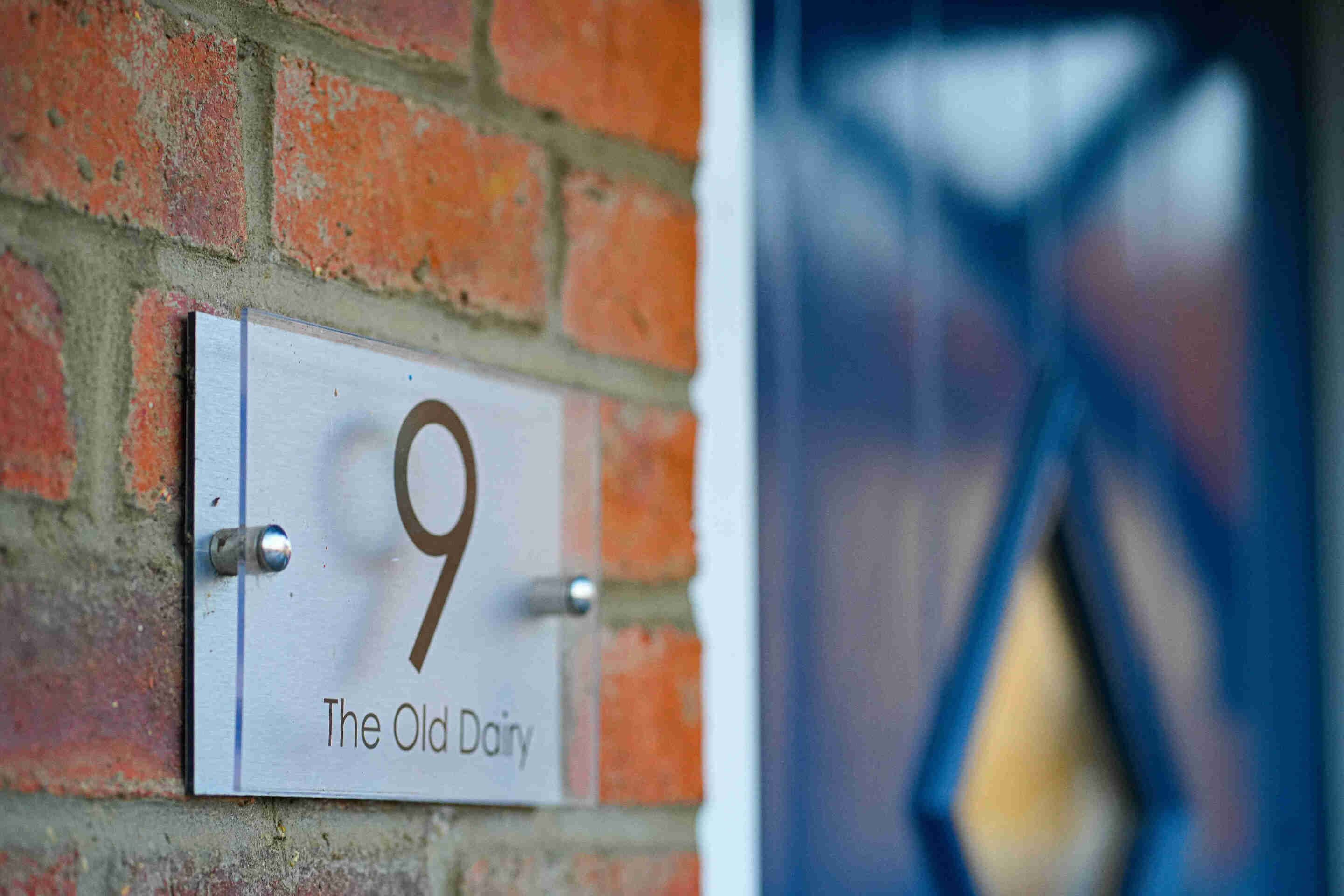 A house number sign with '9' and 'The Old Dairy' text on a brick wall.
