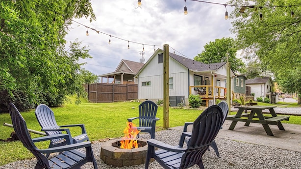 Et udendørs opholdsområde med Adirondack-stole, et bålsted og et picnicbord.