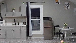 A compact kitchen with a dining area, featuring cabinets, a refrigerator, and a table with chairs.