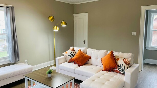 A living room with a white sofa, a coffee table, and a floor lamp. - The Stargazer Sunroom 2bedroom in West CLE (Cleveland)