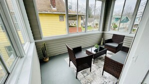 A covered patio with wicker furniture and a potted plant. - The Stargazer Sunroom 2bedroom in West CLE (Cleveland)