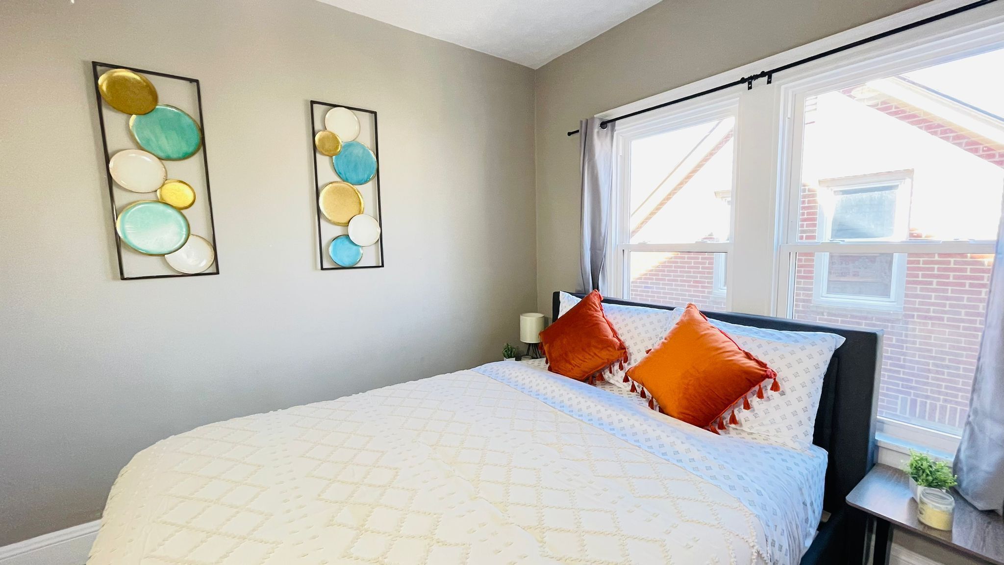 A bedroom with a bed, pillows, a nightstand, a window, and wall art.