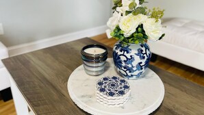 Een ronde tafel met een wit marmeren blad, een blauw-witte vaas met witte bloemen, een kaars en een decoratief bord.