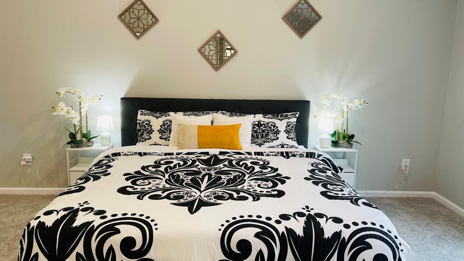Une chambre à coucher avec un grand lit, une table de chevet, une commode et des éléments décoratifs sur les murs.