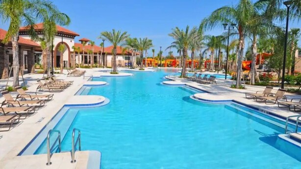 A large swimming pool with multiple lanes, surrounded by palm trees and lounge chairs. - This townhouse is a 5 bedroom(s), 4.5 bathrooms, located in Davenport, FL. (Davenport)