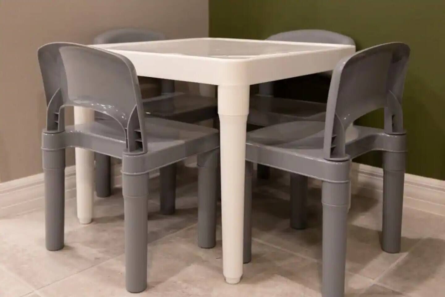 A small dining area with a white table and four grey chairs.
