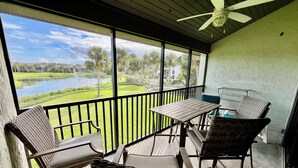 A balcony with wicker furniture, a table, and a view of a lake and greenery. - Gold-rated 2 bed/2 bath condo with view of the lagoon, just steps to the pool. (Saint Augustine)