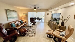 A living room with leather sofas, a TV, and a ceiling fan. - Awesome condo, steps to the heated indoor/outdoor pool, short walk to the beach! (Saint Augustine)