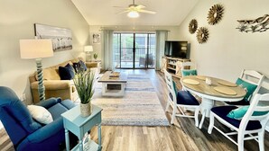 A spacious living room with a sofa, a coffee table, and a dining area with chairs and a table. - Great property perfect for a couples getaway to the beach, steps to pool & sand! (Saint Augustine)