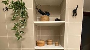 A bathroom with beige tiles, a hanging plant, shelves with baskets and small plants, and a toilet. - 1 Bedroom Apartment in Salerno (Salerno)