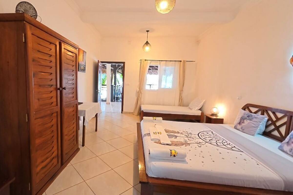 A bedroom with a large bed, a wardrobe, and a door leading to a balcony.