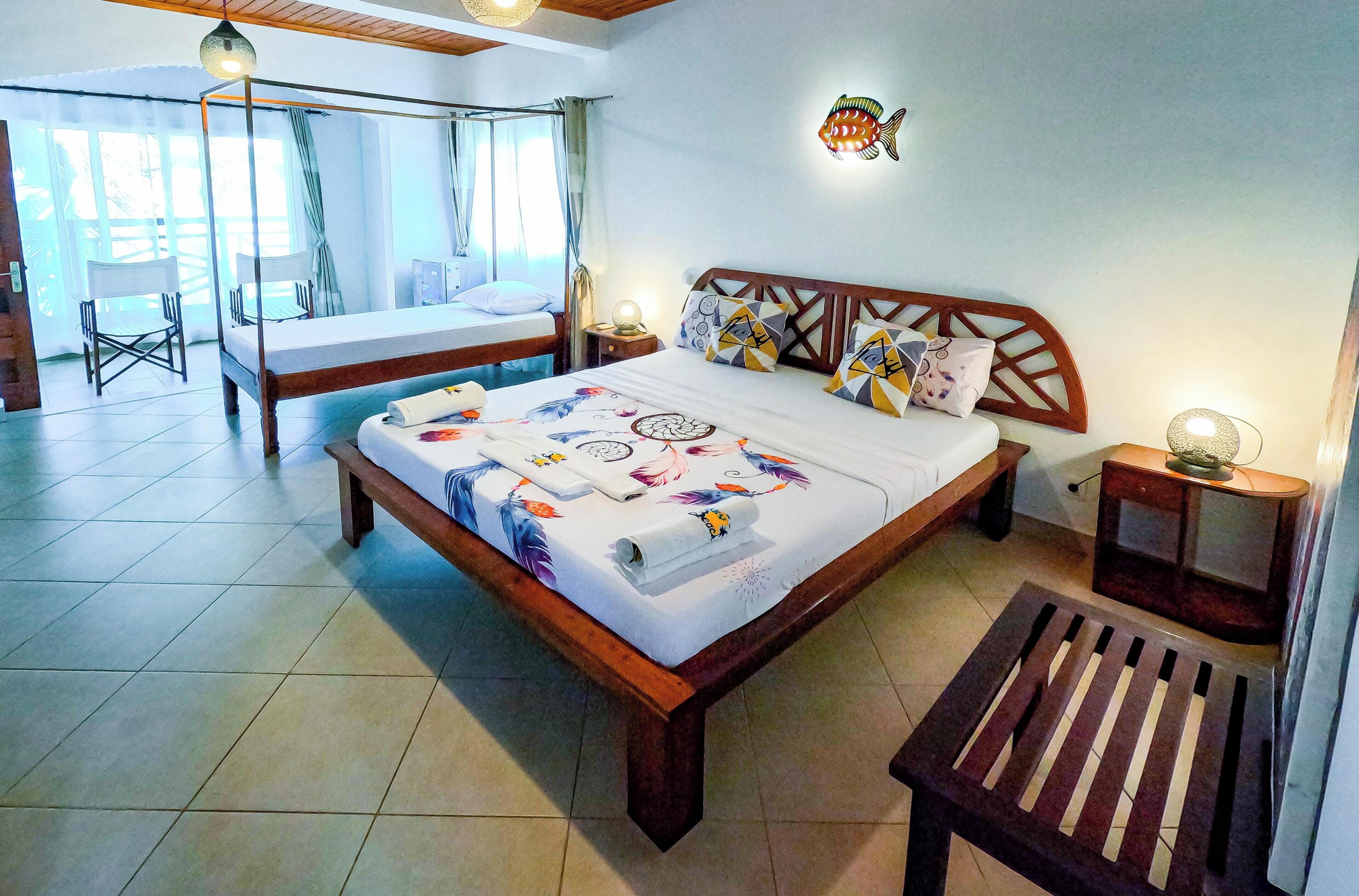 Un dormitorio con techo de madera, una cama con ropa de cama estampada, una mesita de noche con lámpara y un adorno de pez montado en la pared.