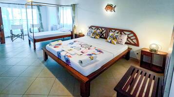 Un dormitorio con techo de madera, una cama con ropa de cama estampada, una mesita de noche con lámpara y un adorno de pez montado en la pared.