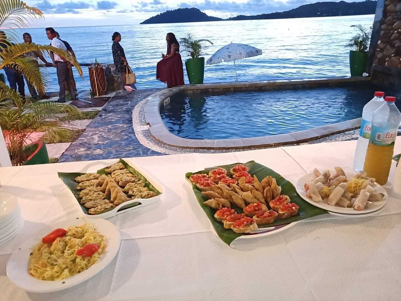 A poolside dining area with a view of the sea and mountains.
