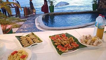 A poolside dining area with a view of the sea and mountains.