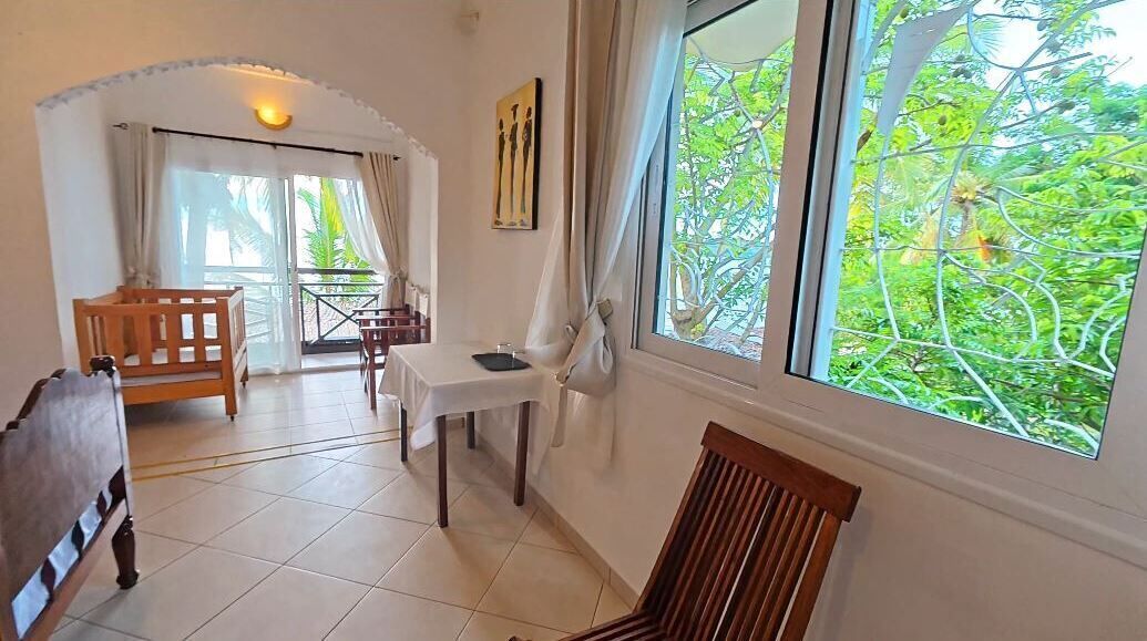 Une pièce comprenant un lit, une table et une chaise. Il y a une fenêtre donnant sur un paysage verdoyant.