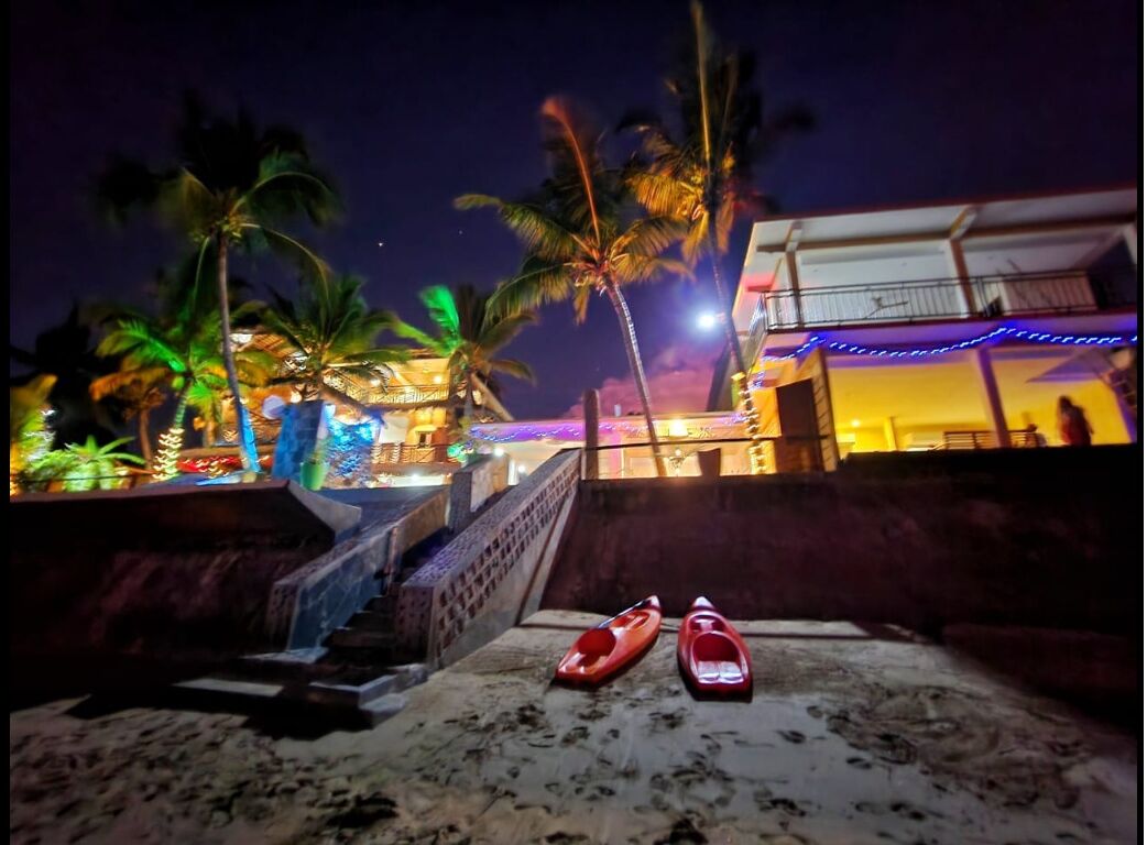 Una vista notturna di una spiaggia con palme e un edificio con finestre illuminate.