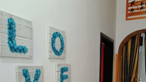 Un couloir dans lequel sont accrochées quatre œuvres d’art aux murs, formant ensemble le mot « AMOUR » en bleu.