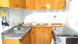 Une cuisine avec des meubles en bois, un évier en acier inoxydable et un dosseret carrelé.