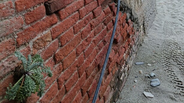Un mur de briques avec un tuyau d’évacuation et un mur de pierres.