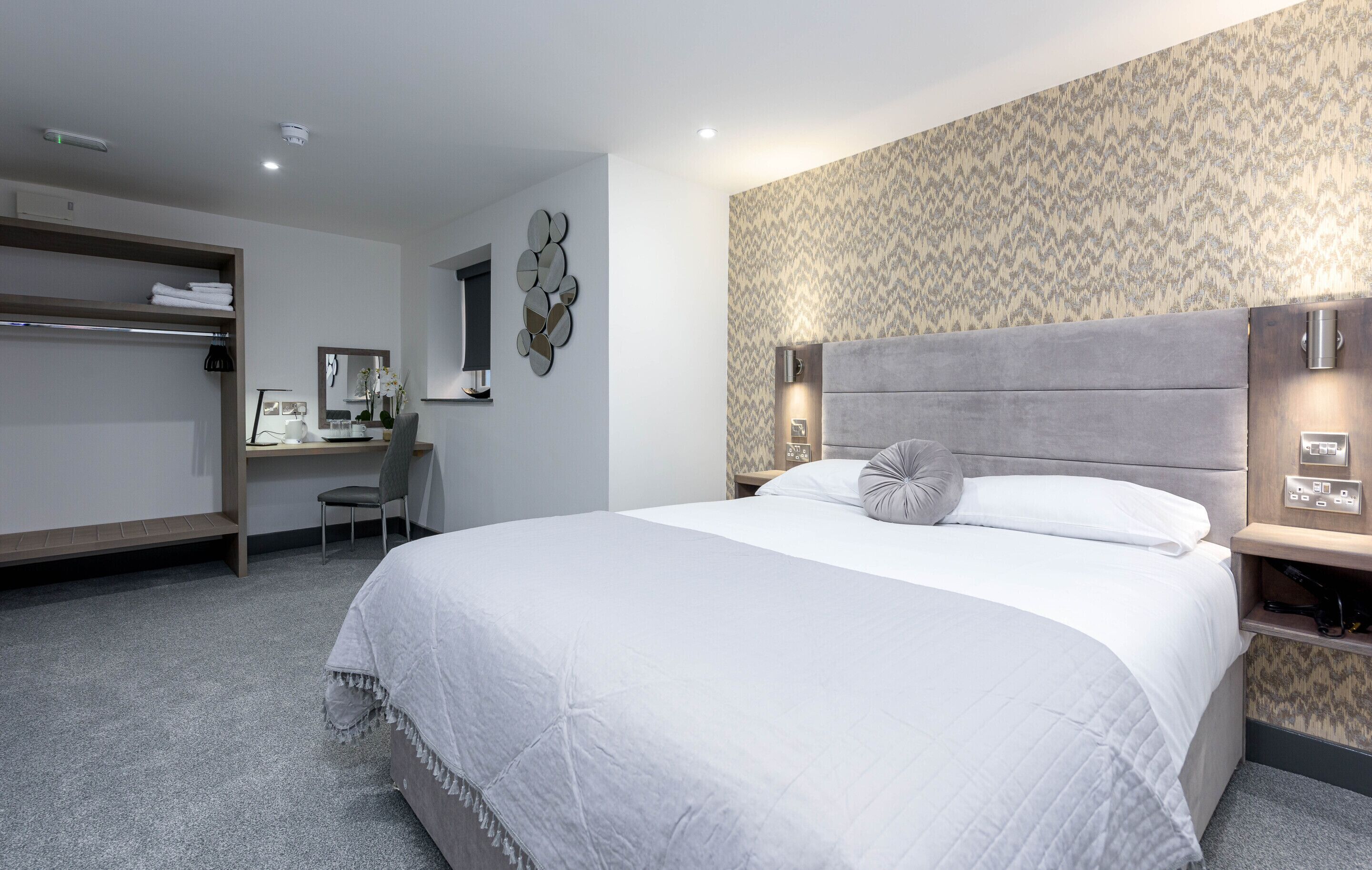 Una habitación de hotel moderna con una cama grande, un escritorio y un armario.