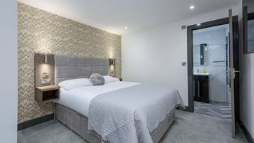 Una habitación de hotel moderna con cama, mesita de noche y estante empotrado.