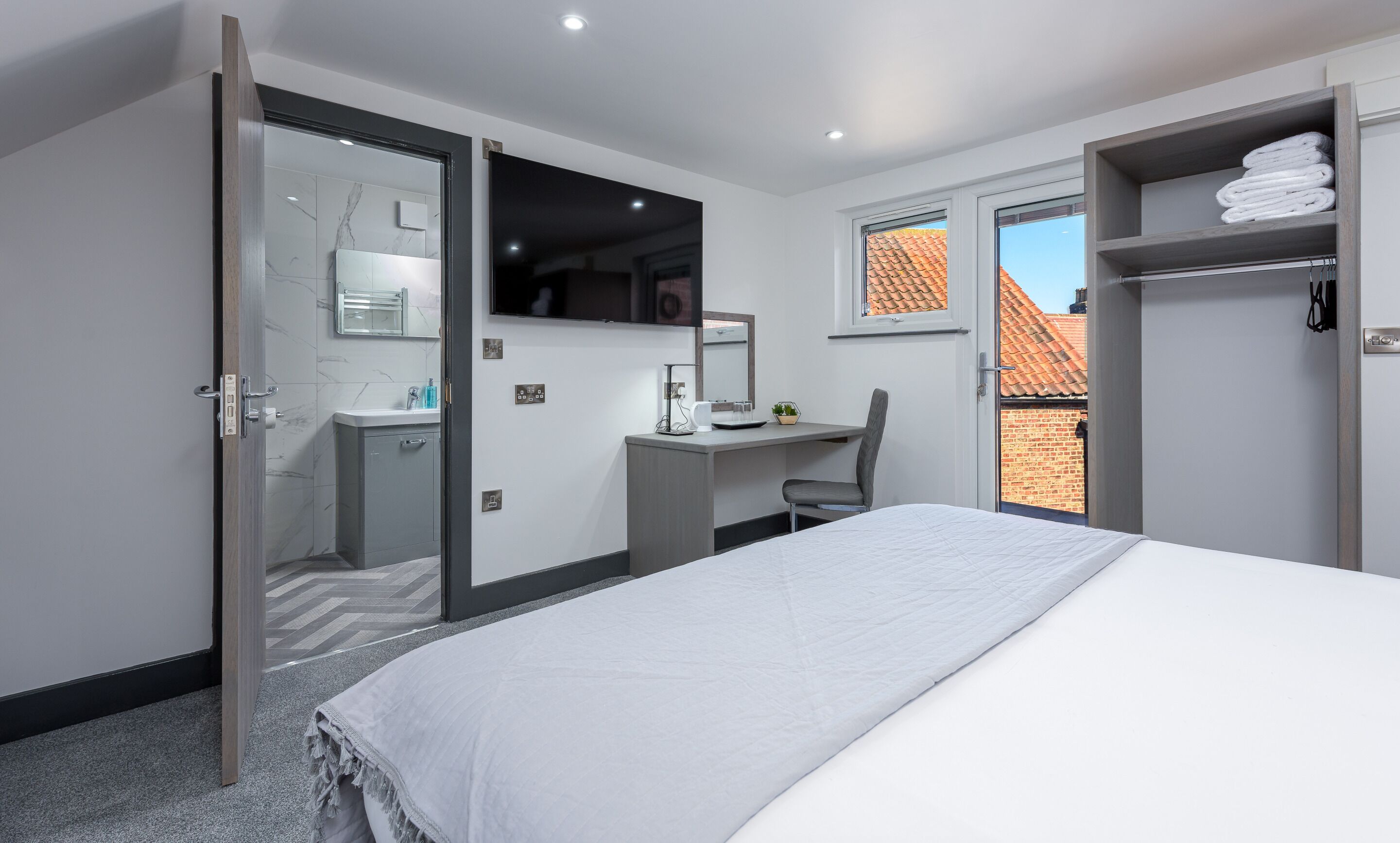 Un dormitorio moderno con cama, escritorio y zona de ducha.