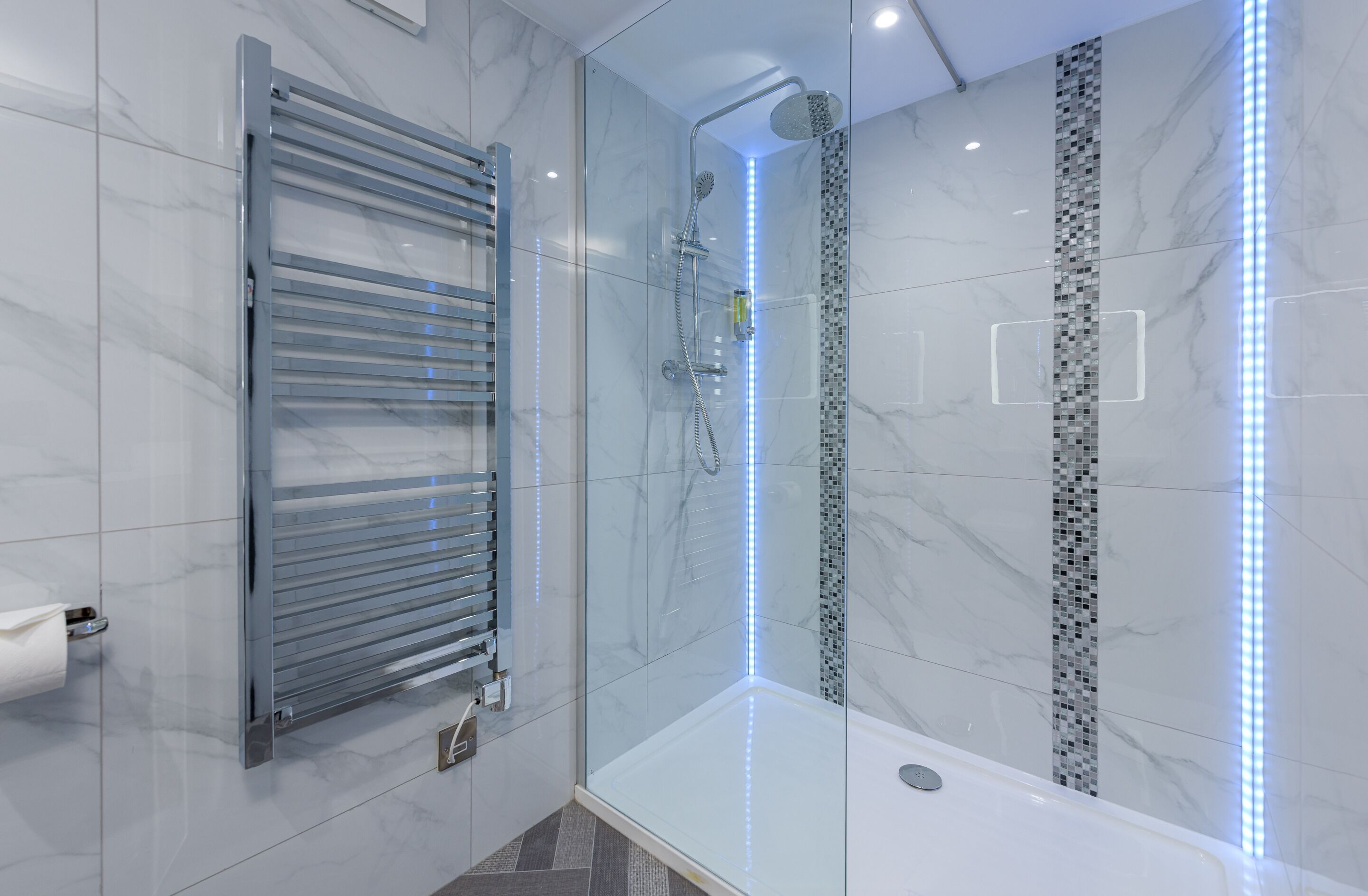 A modern bathroom with a glass-enclosed shower, a glass door, and a tiled floor.