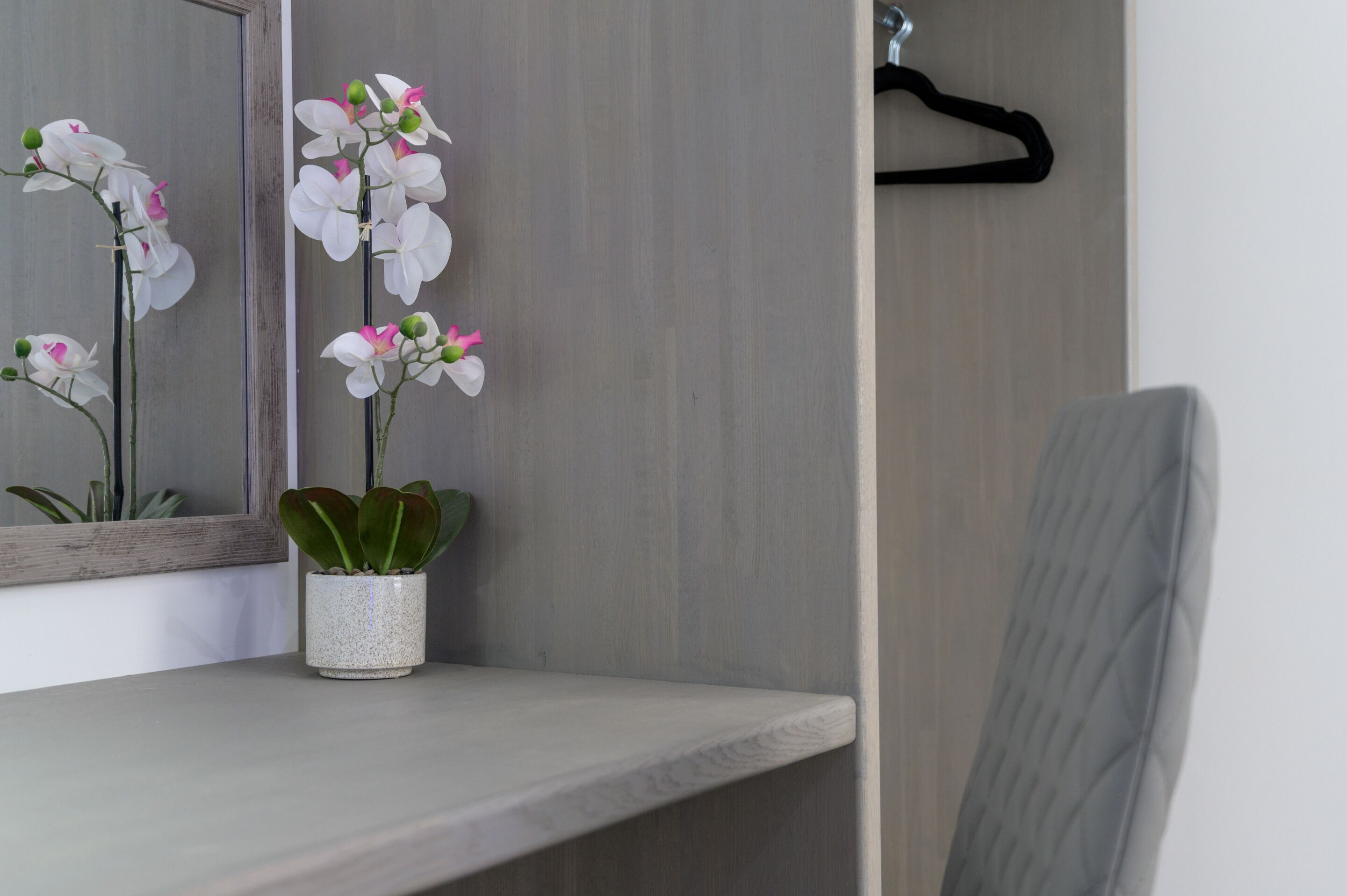 Un baño con espejo, lavabo, toallero y una silla.