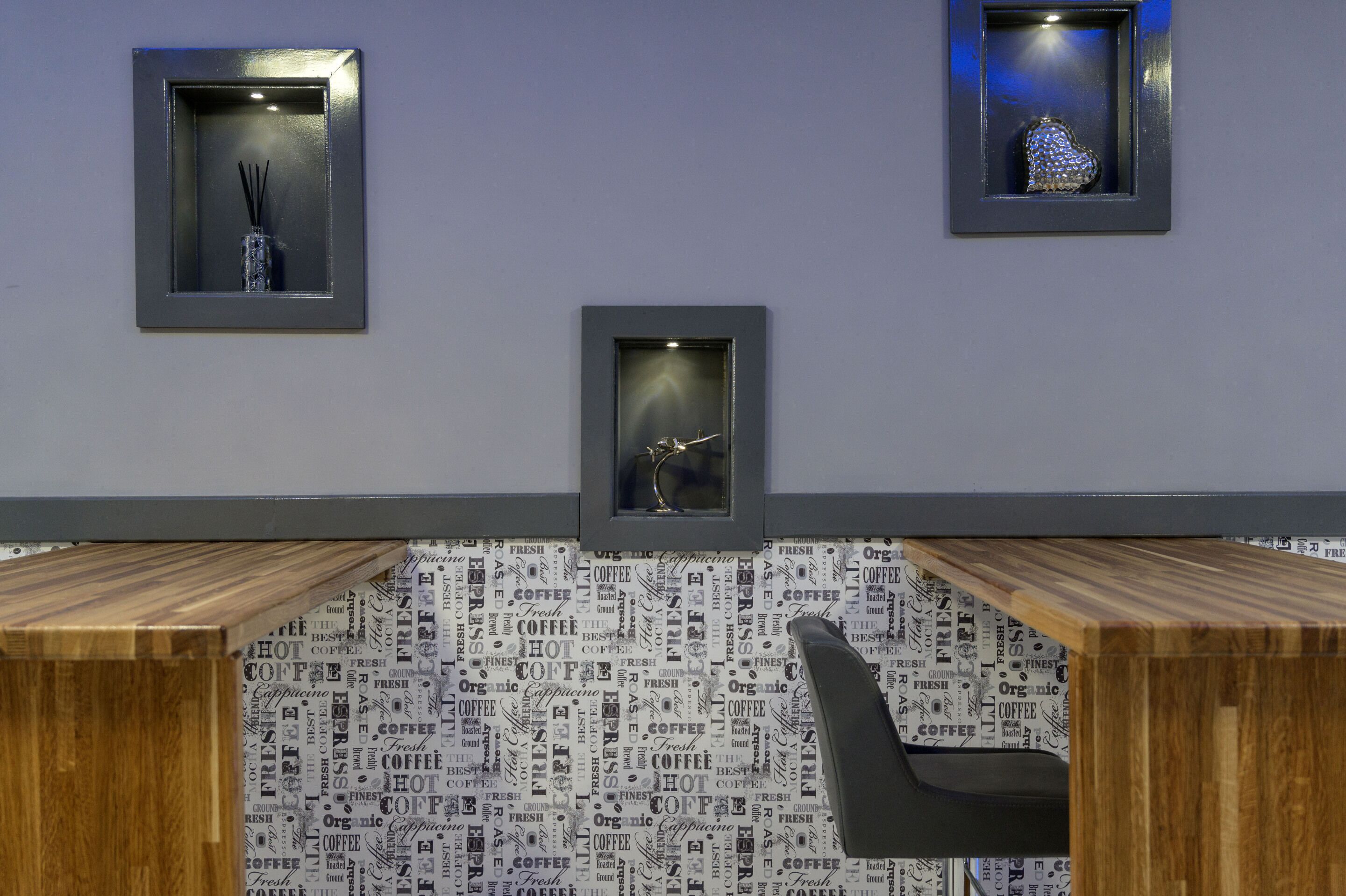 A modern office space with a wooden desk, a chair, and three framed items on the wall.