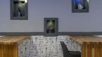A modern office space with a wooden desk, a chair, and three framed items on the wall.