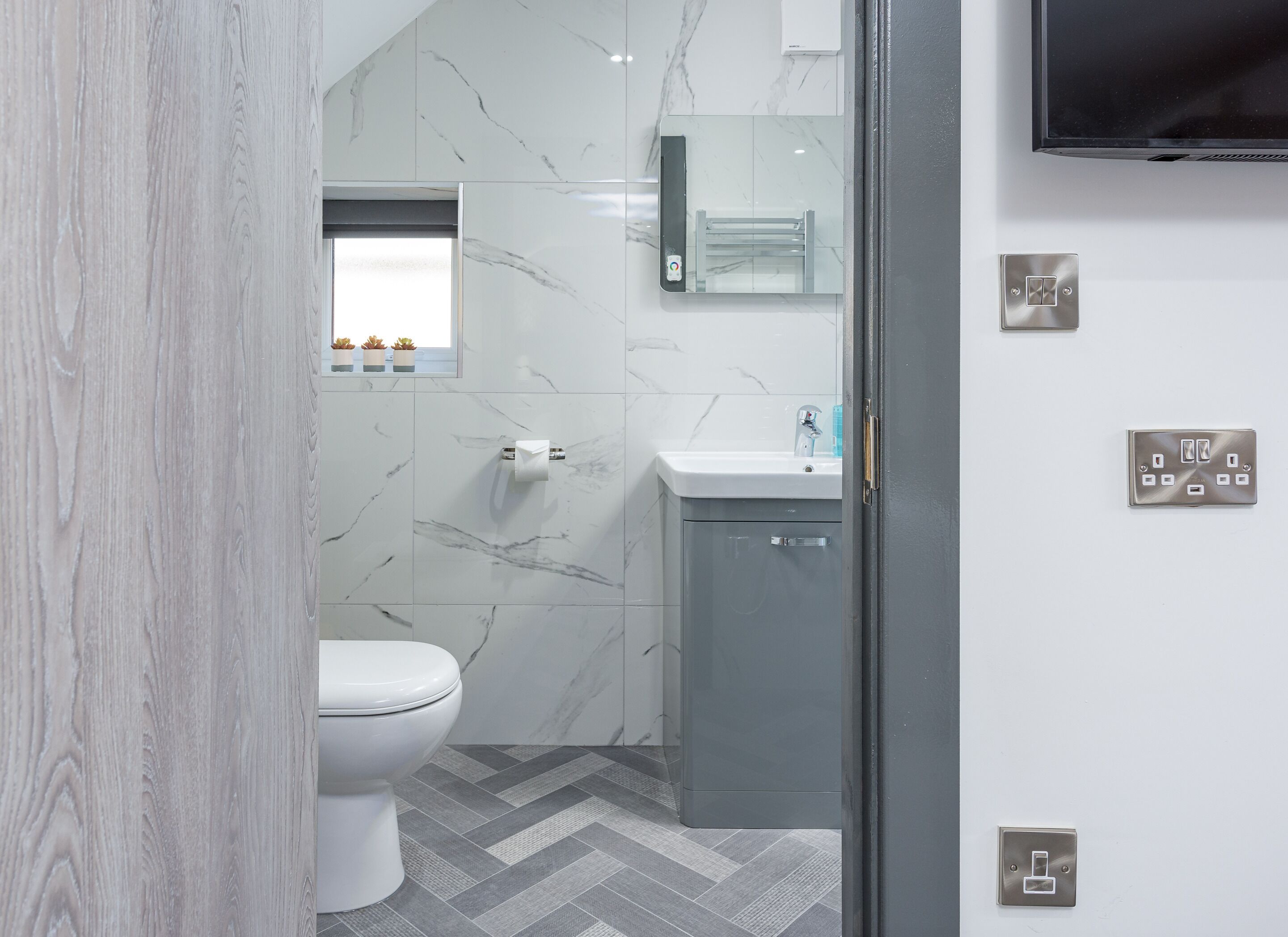 A modern bathroom with a toilet, sink, and mirror.