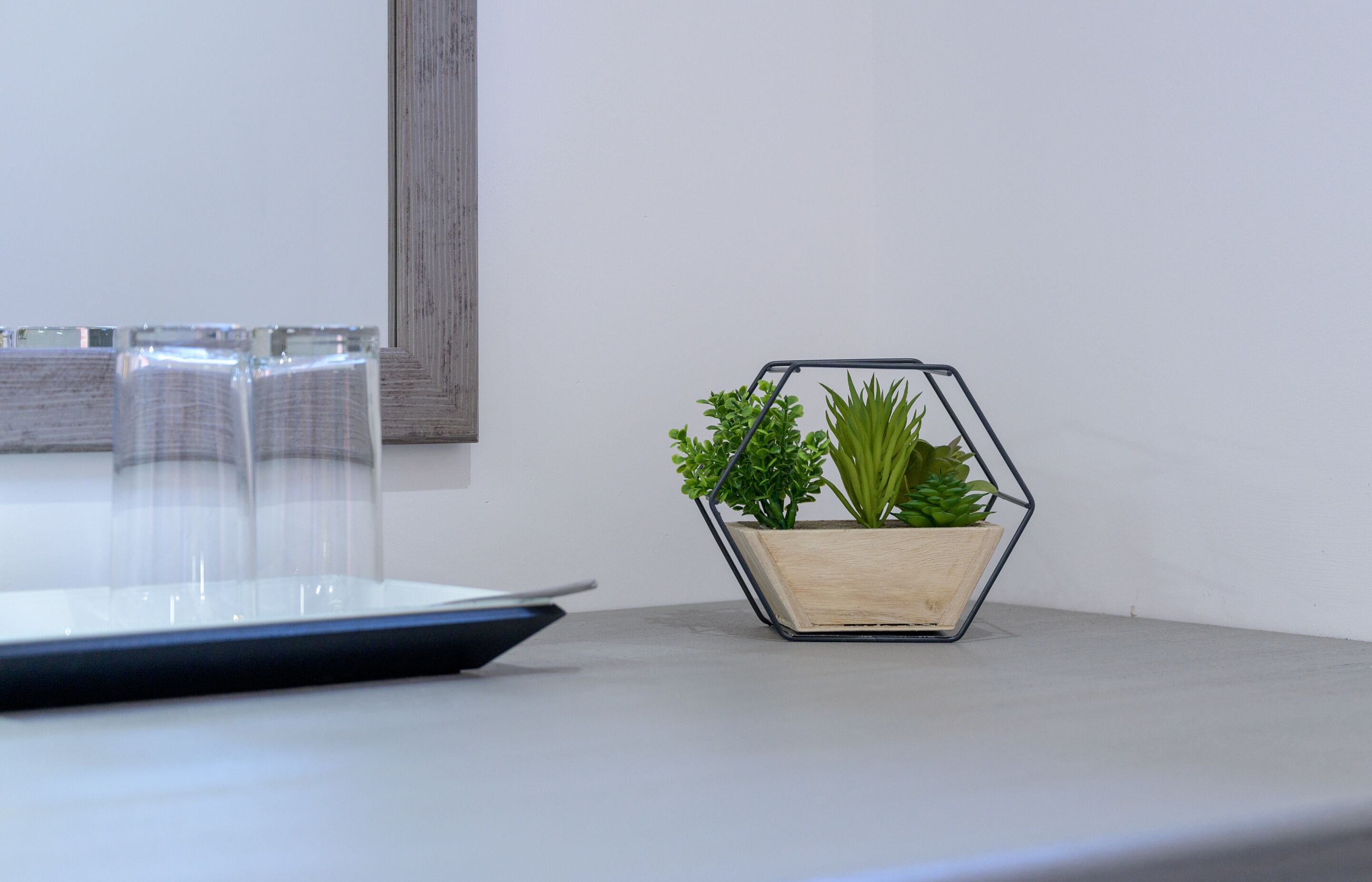 Un pot de fleurs hexagonal sur lequel sont posées deux plantes vertes, le tout étant placé sur une table.