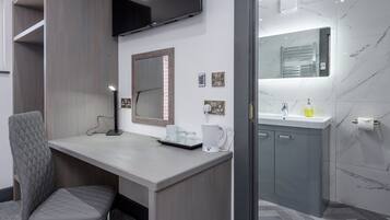 Een moderne badkamer met een marmeren wand, een ingebouwd wastafelmeubel, een spiegel en een toiletrolhouder.