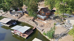 A riverside property with a dock, a house with a balcony, and a small garden area. - Quiet Cove, Lake Views, Grill, Private Dock (Sunrise Beach)