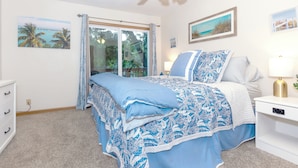 A bedroom with a bed, a nightstand, a ceiling fan, and a window with curtains.