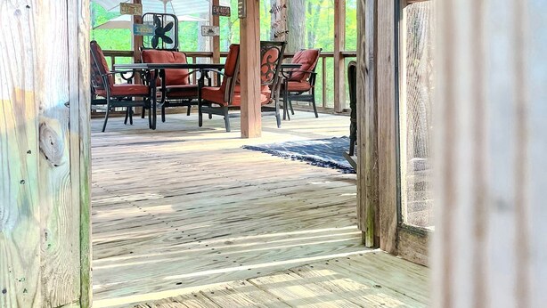 A wooden deck with a covered seating area, including a table and chairs, and directional signs. - Wake up in Waxhaw (Waxhaw)