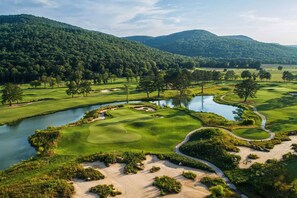 A golf course with a water body, sand bunkers, and surrounding greenery.