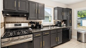 Una cocina moderna con gabinetes oscuros, electrodomésticos de acero inoxidable y un ventanal que proporciona luz natural.