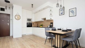 Una cocina moderna con armarios blancos, encimera de madera y un comedor con mesa y sillas.