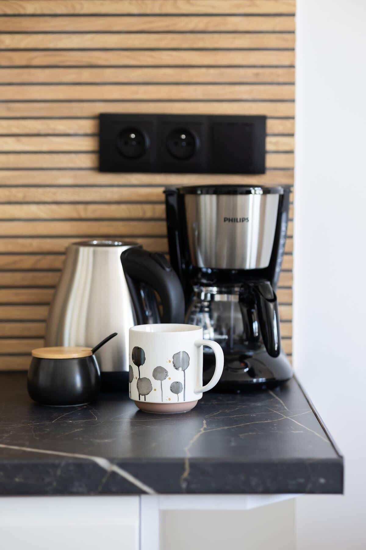 Un piano di lavoro in cucina con una macchina da caffè, un bollitore e una tazza.