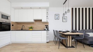 Una cocina moderna con armarios blancos, encimera de madera y una zona de comedor con mesa y sillas.