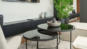 A modern living room with a sofa, a round table with a bowl, a potted plant, and a large mirror on the wall. - Spacious Apartment with Balcony | Parking | Close to Park (Wroclaw)