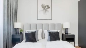 A modern bedroom with a bed, two bedside tables, a wall-mounted lamp, and a framed artwork. - Spacious Apartment with Balcony | Parking | Close to Park (Wroclaw)
