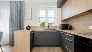 A modern kitchen with a wooden countertop, black cabinets, a sink, and a microwave. - Spacious Apartment with Balcony | Parking | Close to Park (Wroclaw)