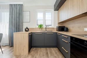 Una cocina moderna con encimera de madera, armarios negros, un fregadero y un microondas.