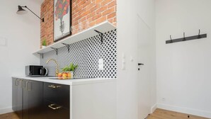 Una cocina moderna con encimera blanca, armarios negros, pared decorativa de ladrillo y salpicadero estampado.