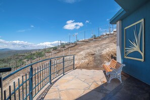 A stone staircase leading to a terrace with a bench, a railing, and a view of the landscape.